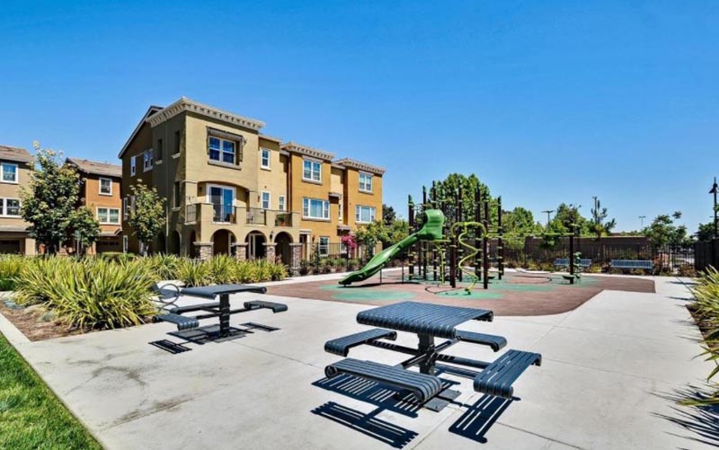 Prima Homeowners Association picnic tables next to playground with building in background